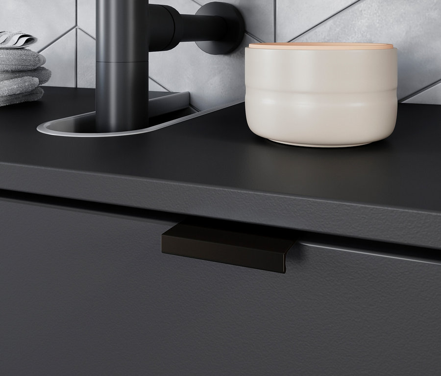 Schwarzer Wasserhahn neben weißem Behälter mit Holzdeckel auf grauer Arbeitsplatte.