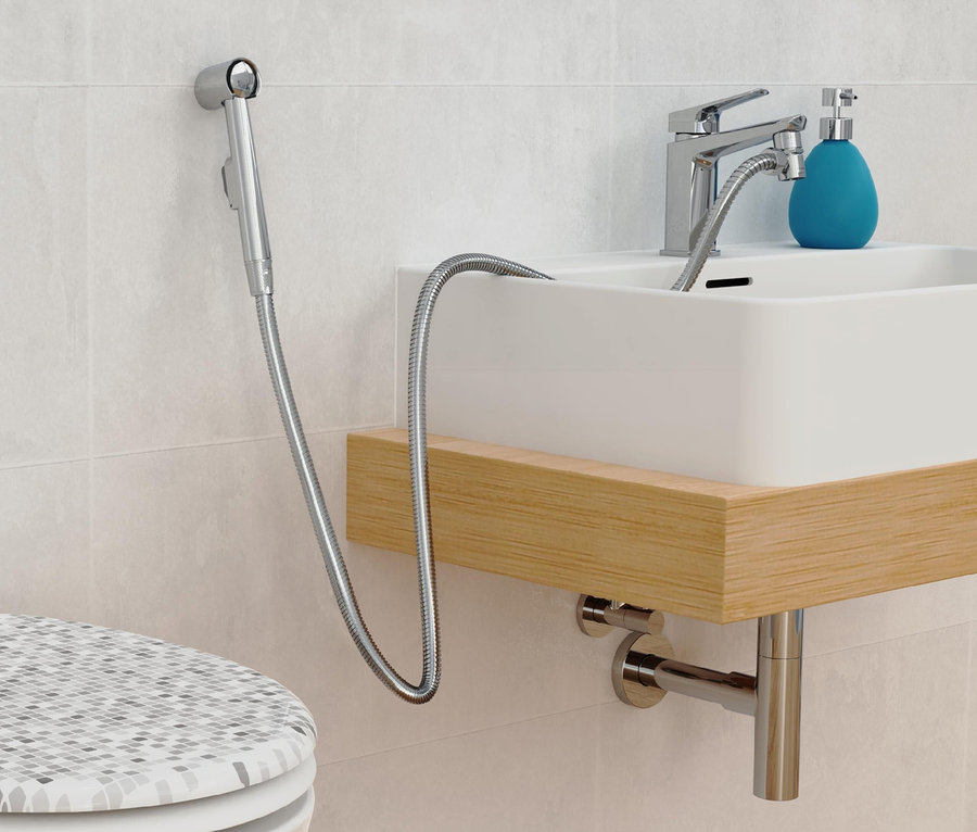 Detailaufnahme eines Badezimmers mit Bidetbrause, Waschbecken und Toilette.