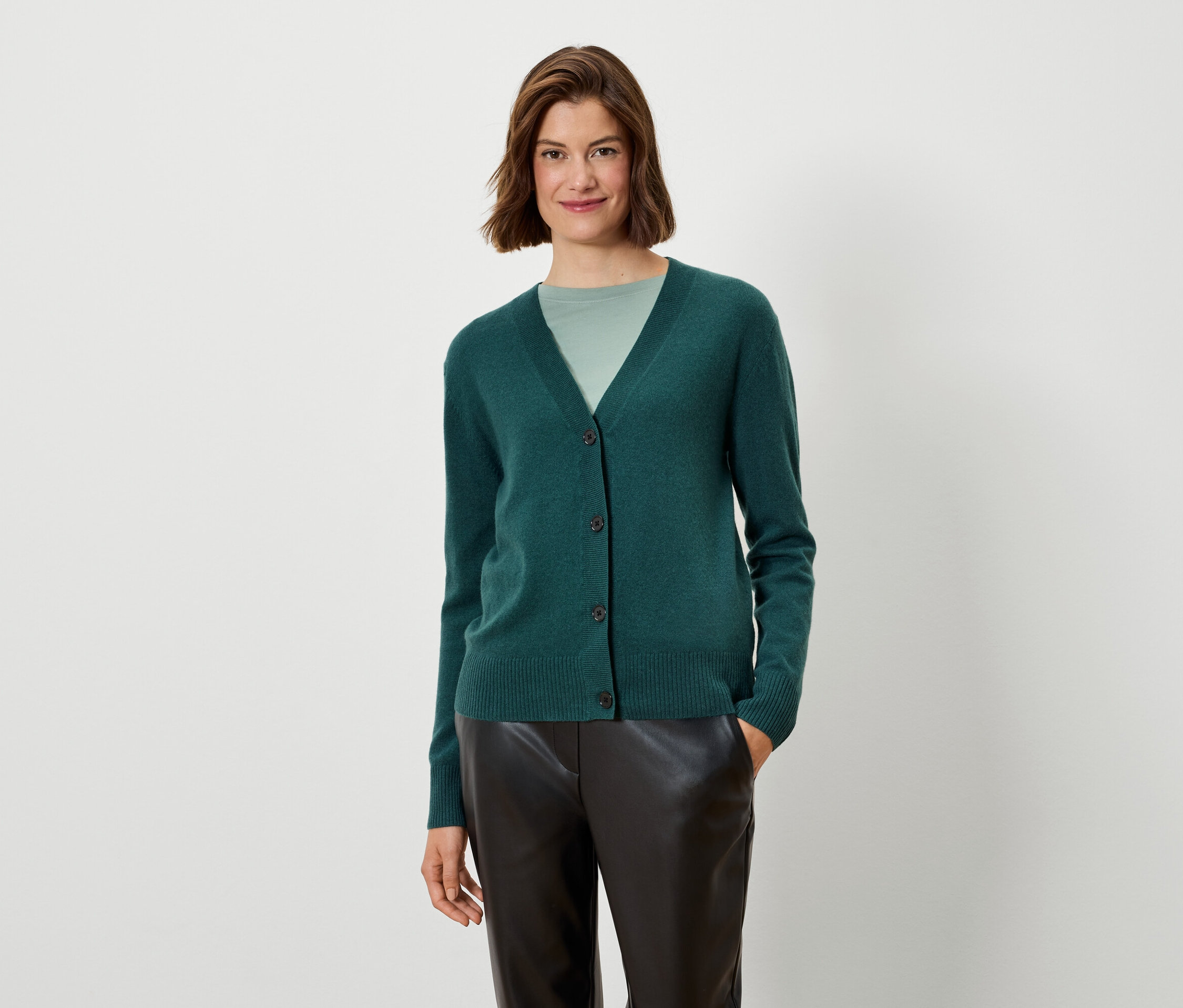 Frau trägt eine grüne Strickjacke und schwarze Hose.