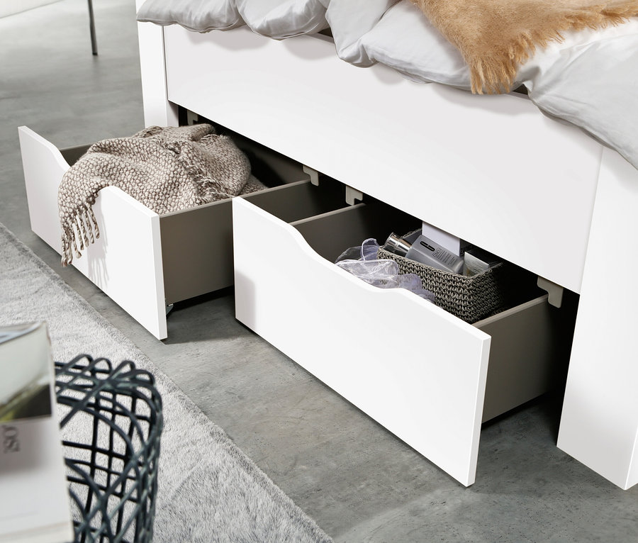 Detailansicht eines weißen Bettes mit offenen Schubladen, wobei eine Schublade eine Decke und die andere einen Korb mit Kosmetika enthält. Rauch Bett »Aditio Beds«, 140 cm