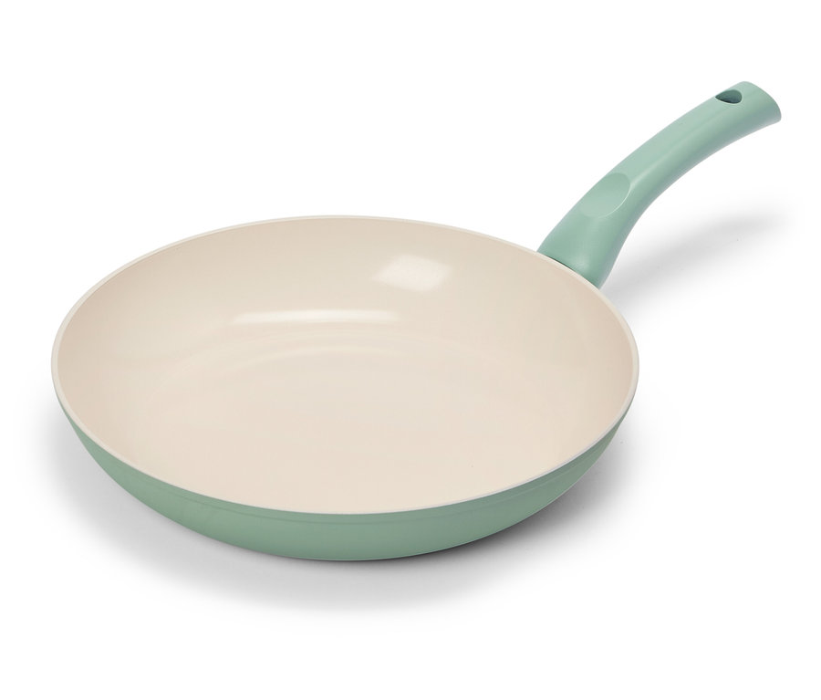 Eine hellgrüne Bratpfanne mit cremefarbener Innenseite liegt auf einem weißen Hintergrund.
