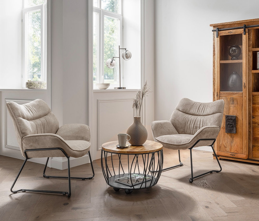 Zwei beige DeVries Sessel »Aliano« stehen im Wohnzimmer auf einem Holzboden.