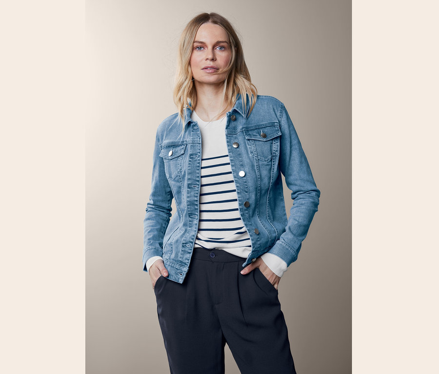 Blonde Frau posiert in blauer Jeansjacke.