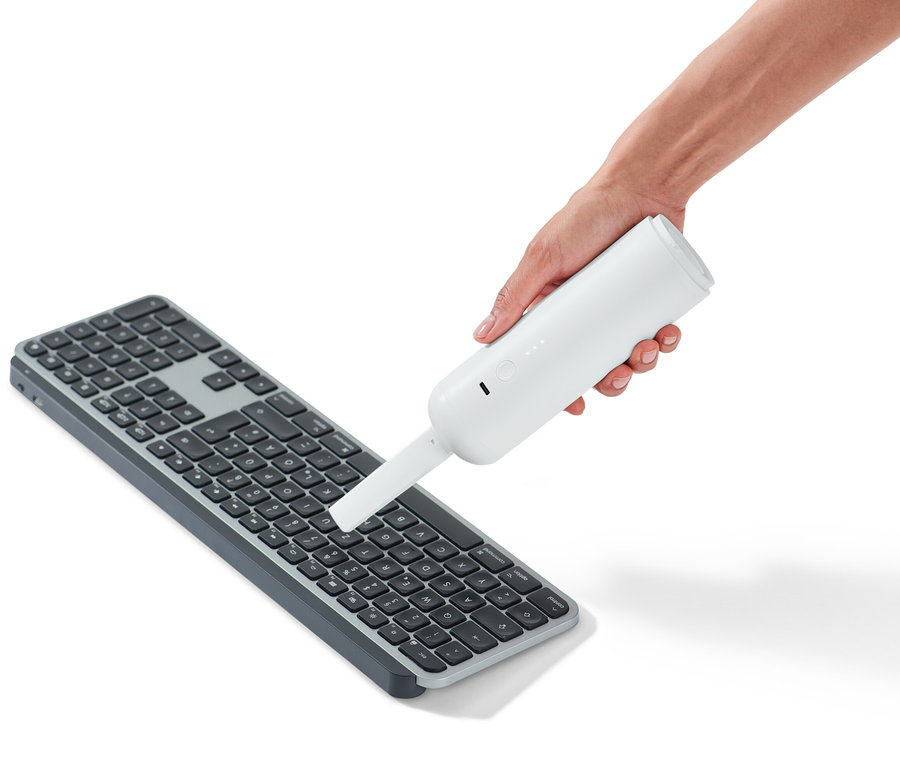 Eine Hand hält einen Akku-Handstaubsauger über eine Tastatur.