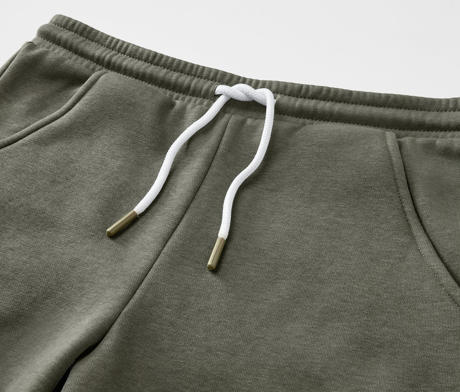 Nahaufnahme von 2 Kinder-Sweatshorts in Olivgrün mit Kordelzug.