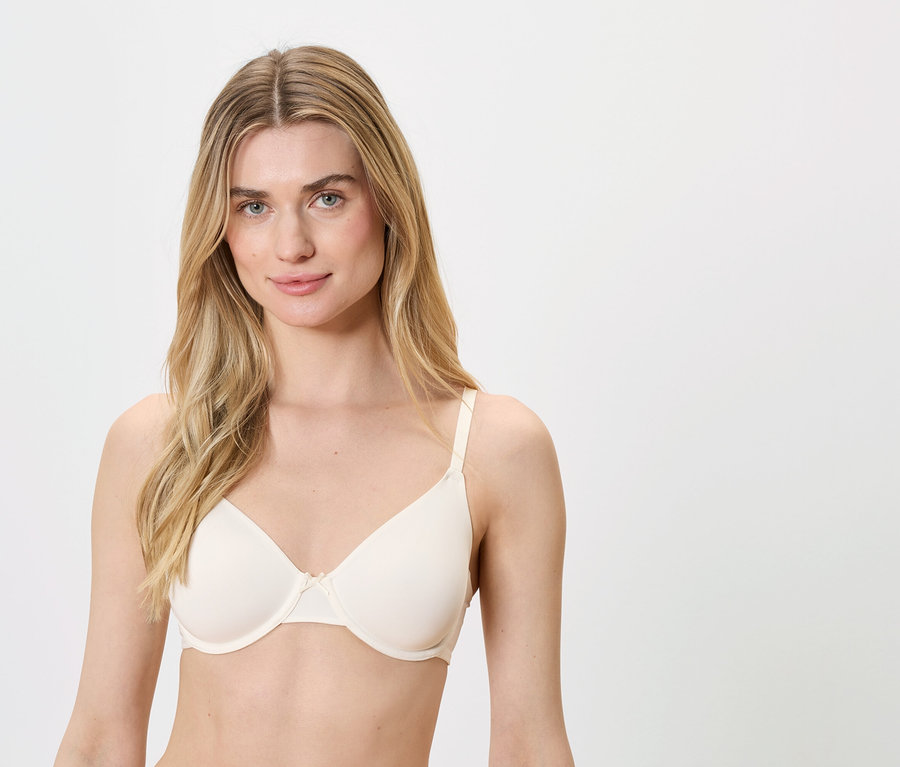 Blonde Frau mit blauen Augen trägt einen hautfarbenen BH.