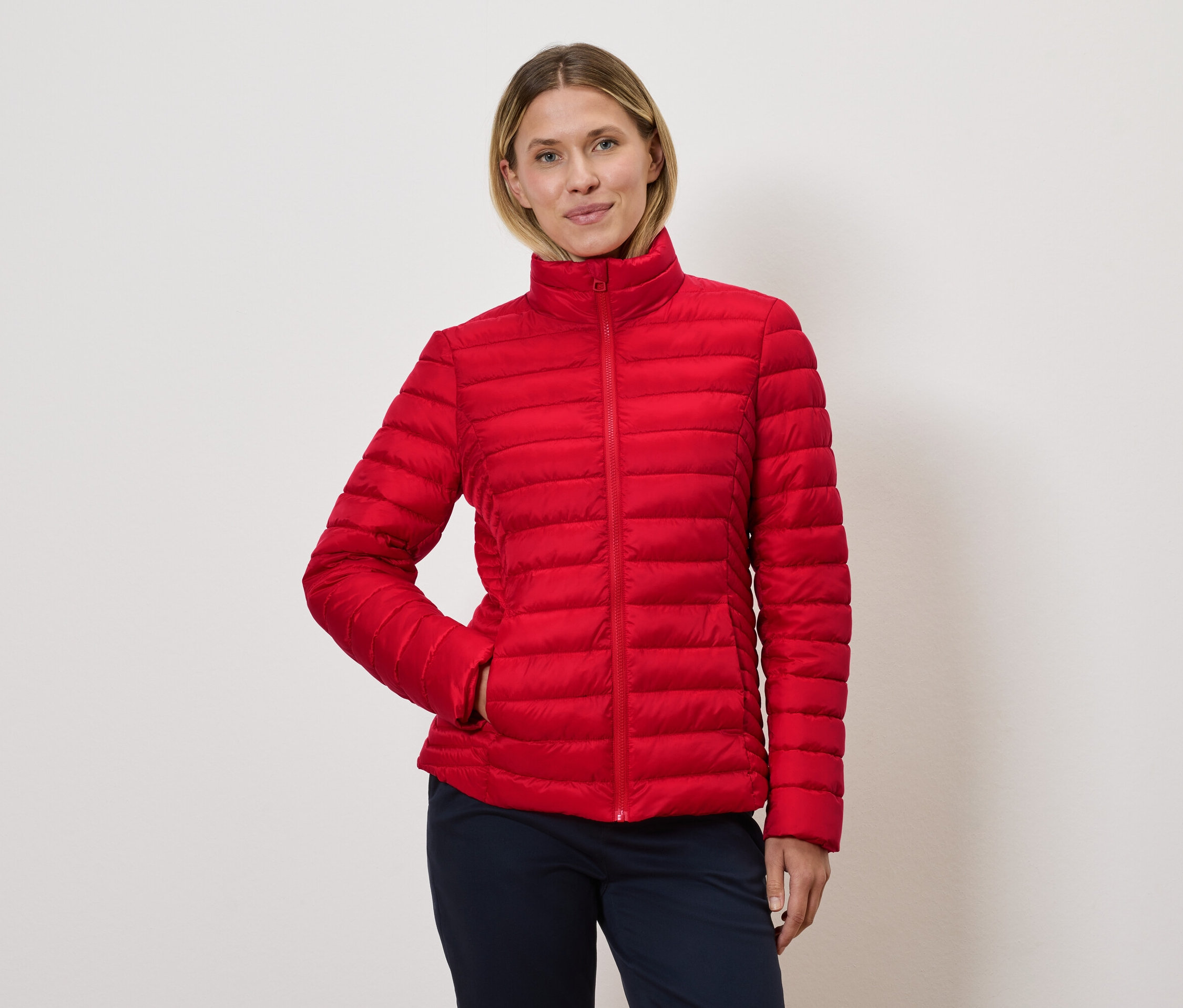 Frau posiert in roter Steppjacke.