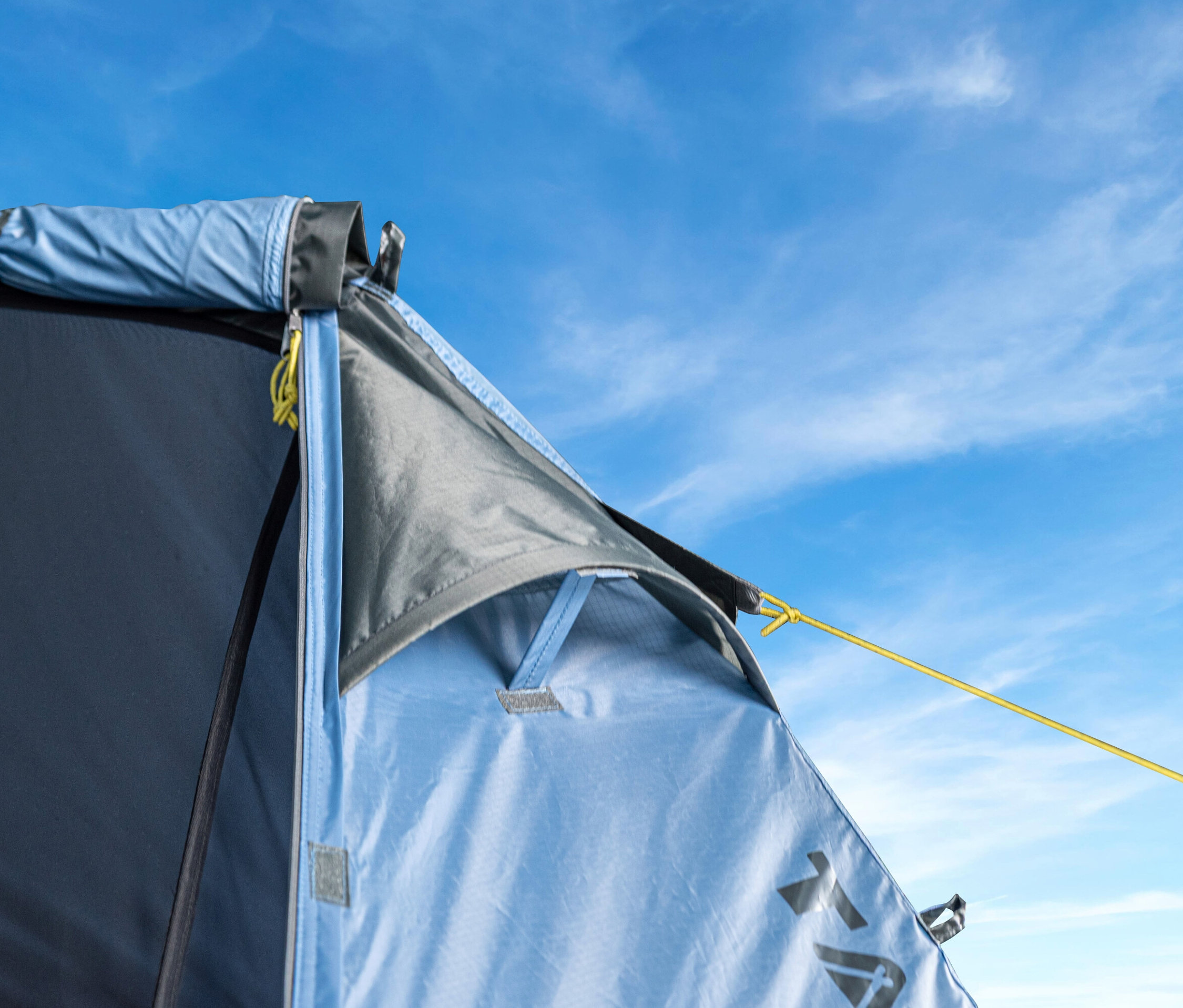 Nahaufnahme vom Eingang des blauen Tambu »TARA 2« 2-Personen-Trekkingzelts vor blauem Himmel.