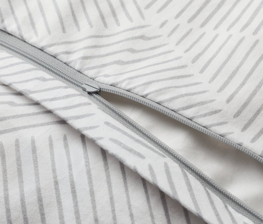 Nahaufnahme eines teilweise geöffneten Bettbezugs mit Reißverschluss und grauem Strichmuster auf weißem Grund.