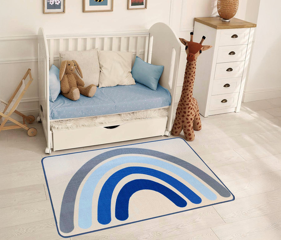 Ein blau gestreifter Kinderteppich »Rainbow« liegt in einem Kinderzimmer mit einem weißen Kinderbett und einer Spielzeuggiraffe.