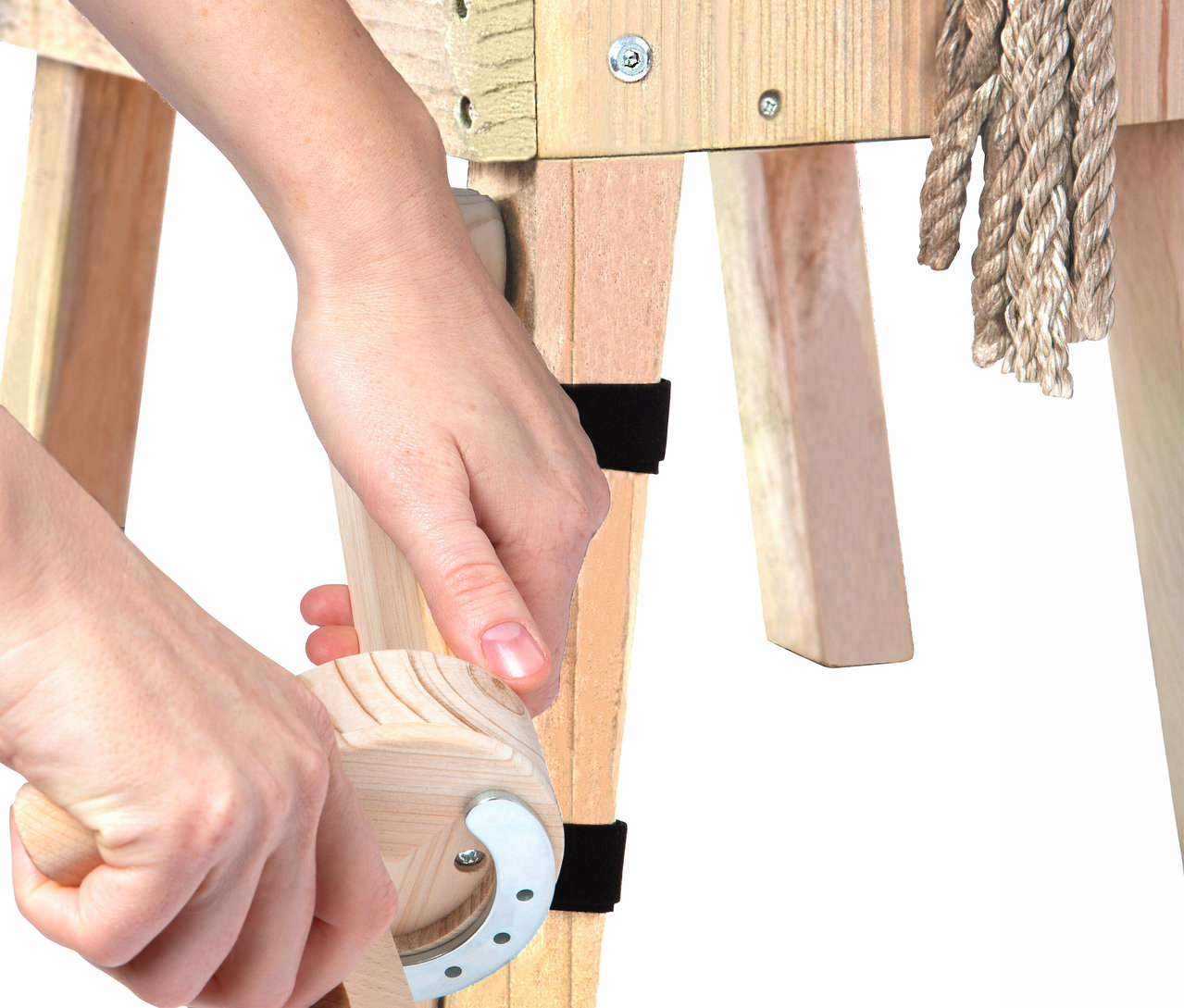 Hände benutzen ein small foot Putzhufe-Set an einem Holzpferd.