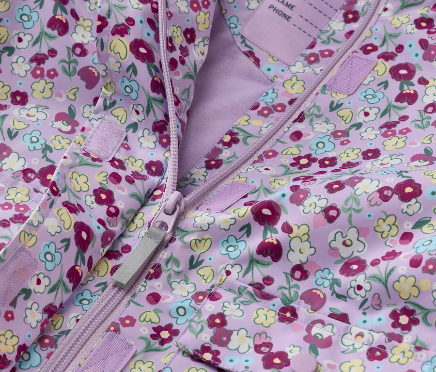 Nahaufnahme einer lila Kinderjacke mit Blumenmuster, offen mit Reißverschluss.