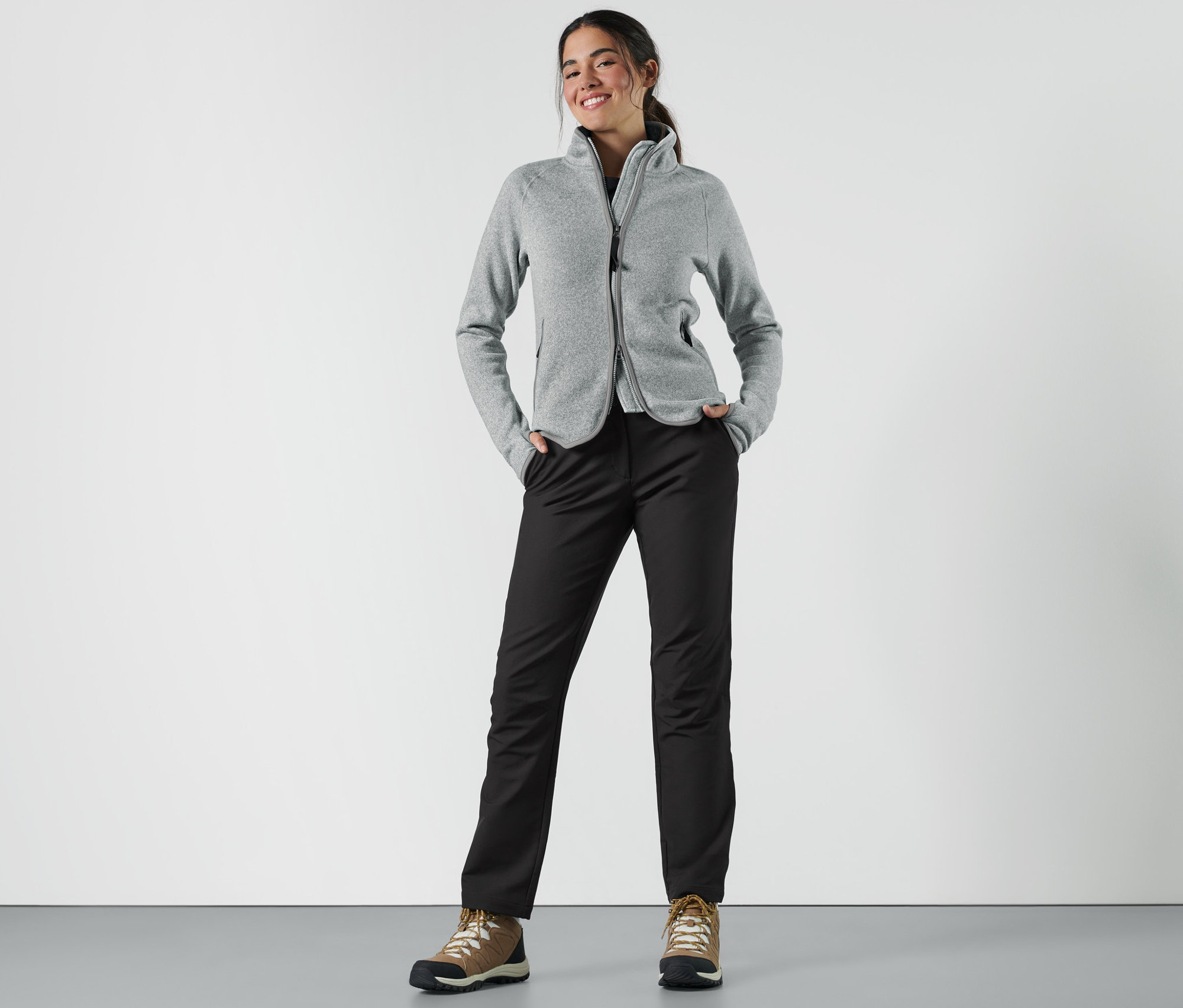 Frau steht mit Händen in den Taschen ihrer Softshellhose.