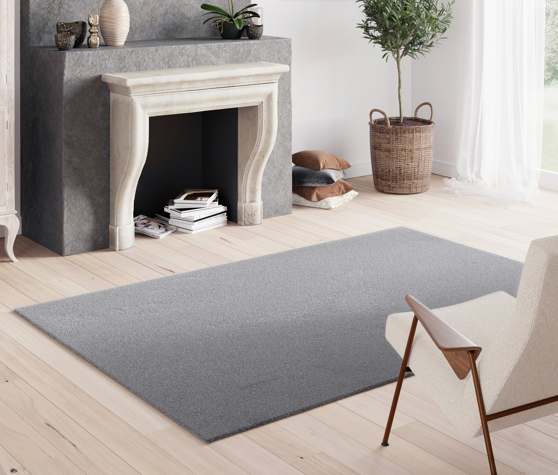 Grauer Teppich »Mellow« liegt auf Holzboden im Wohnzimmer mit Kamin.