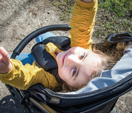Mädchen liegt im schwarzen Osann Sportwagen »Vegas« und schaut nach oben.