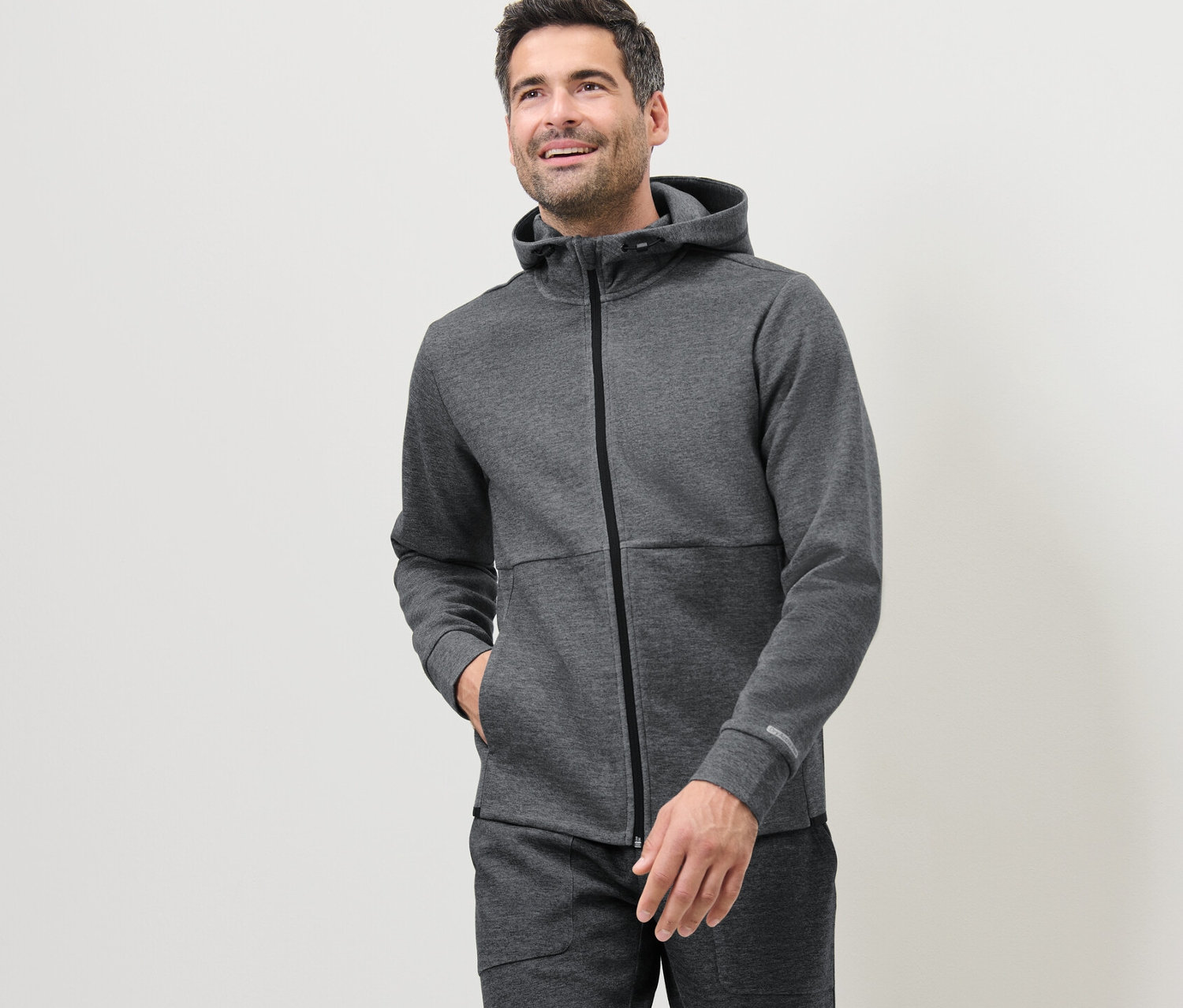 Mann trägt eine graue Funktionssweatjacke.
