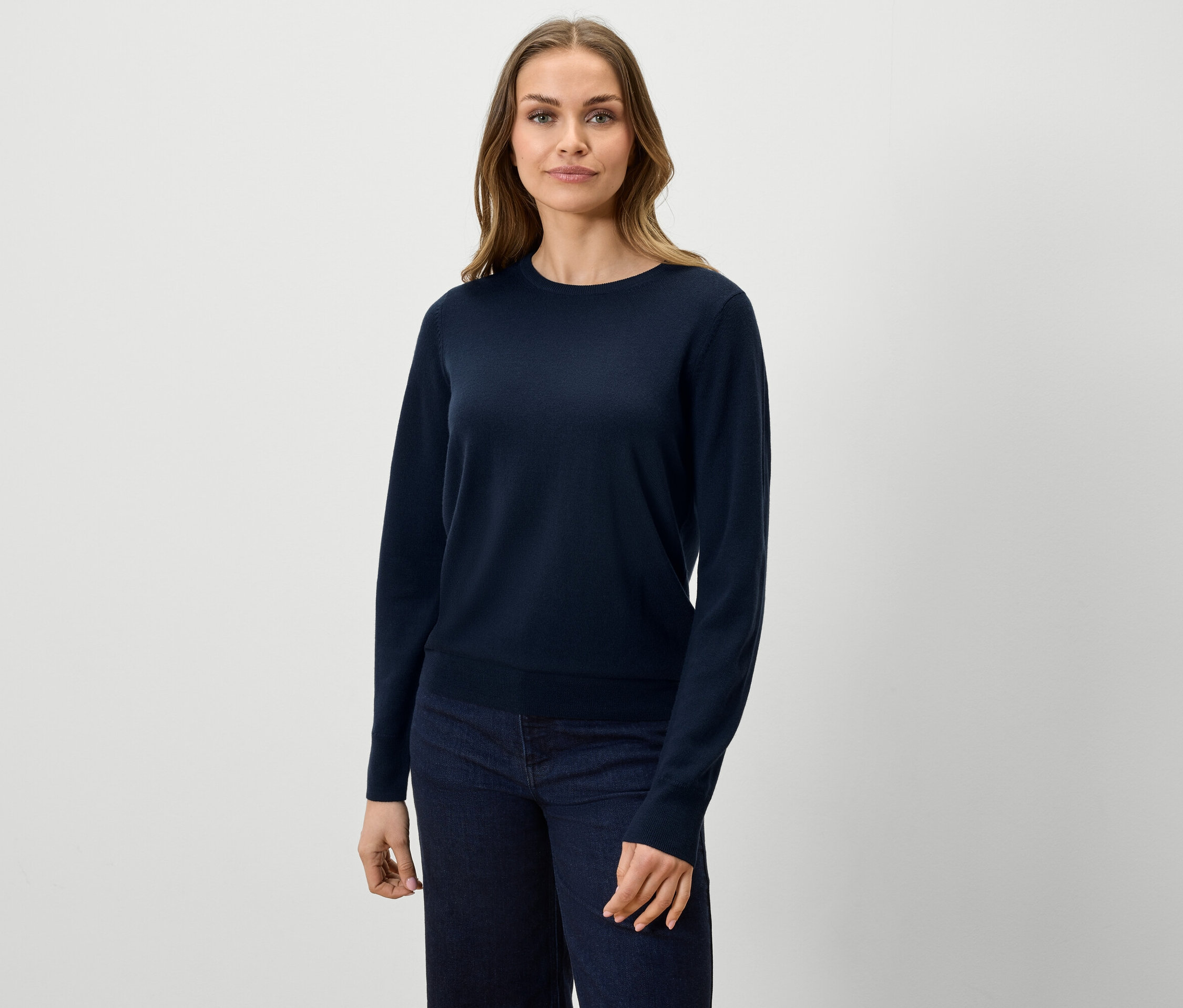 Frau trägt einen dunkelblauen Pullover und Jeans.
