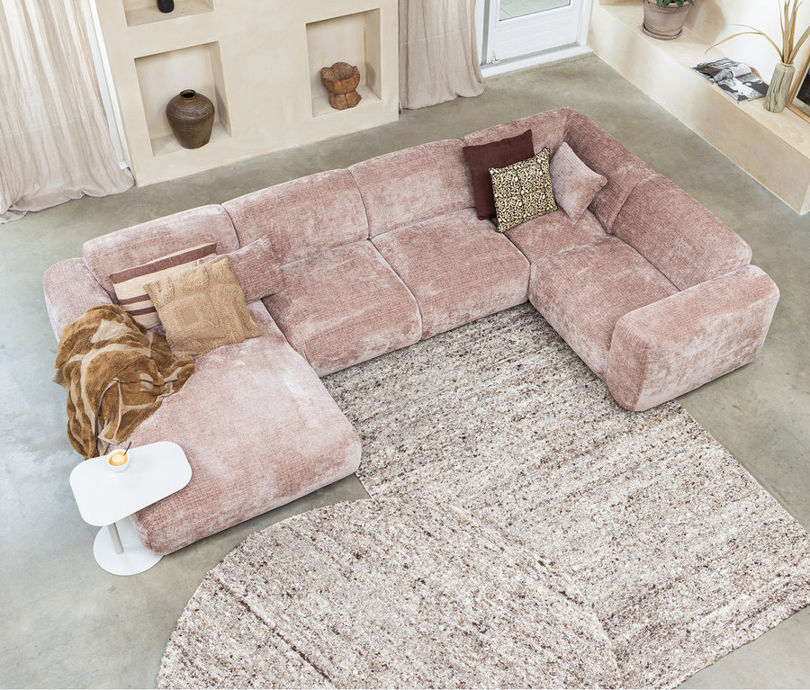 Draufsicht auf ein rosafarbenes Modulsofa mit Kissen auf einem beigen Woood Teppich »Efia«, 170 x 240 cm, neben einem weißen Tisch mit Getränk.