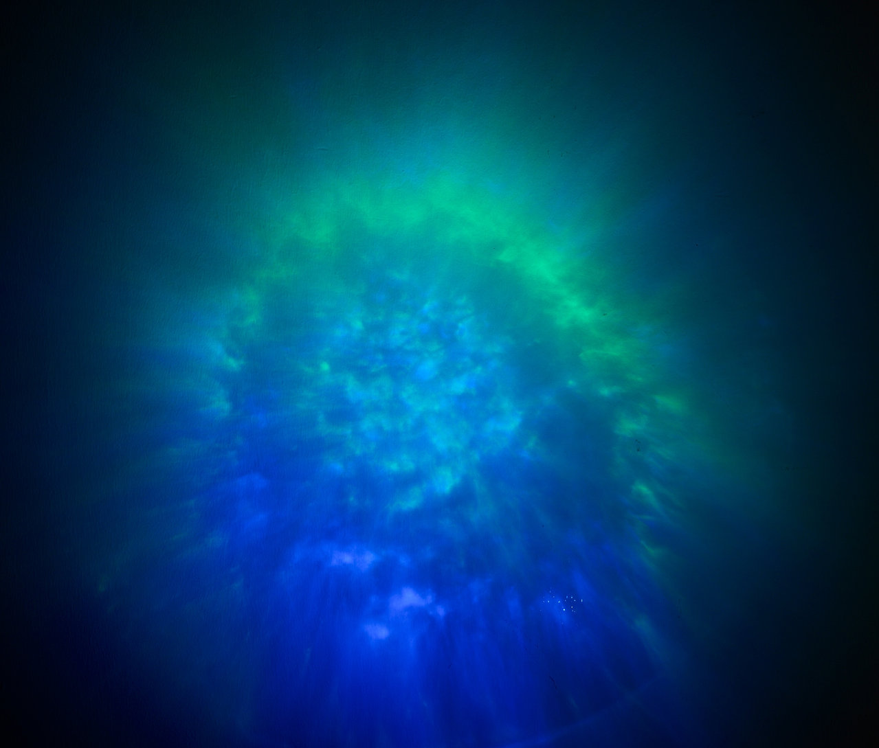 Abstraktes Bild eines blauen und grünen Glühens in der Dunkelheit.