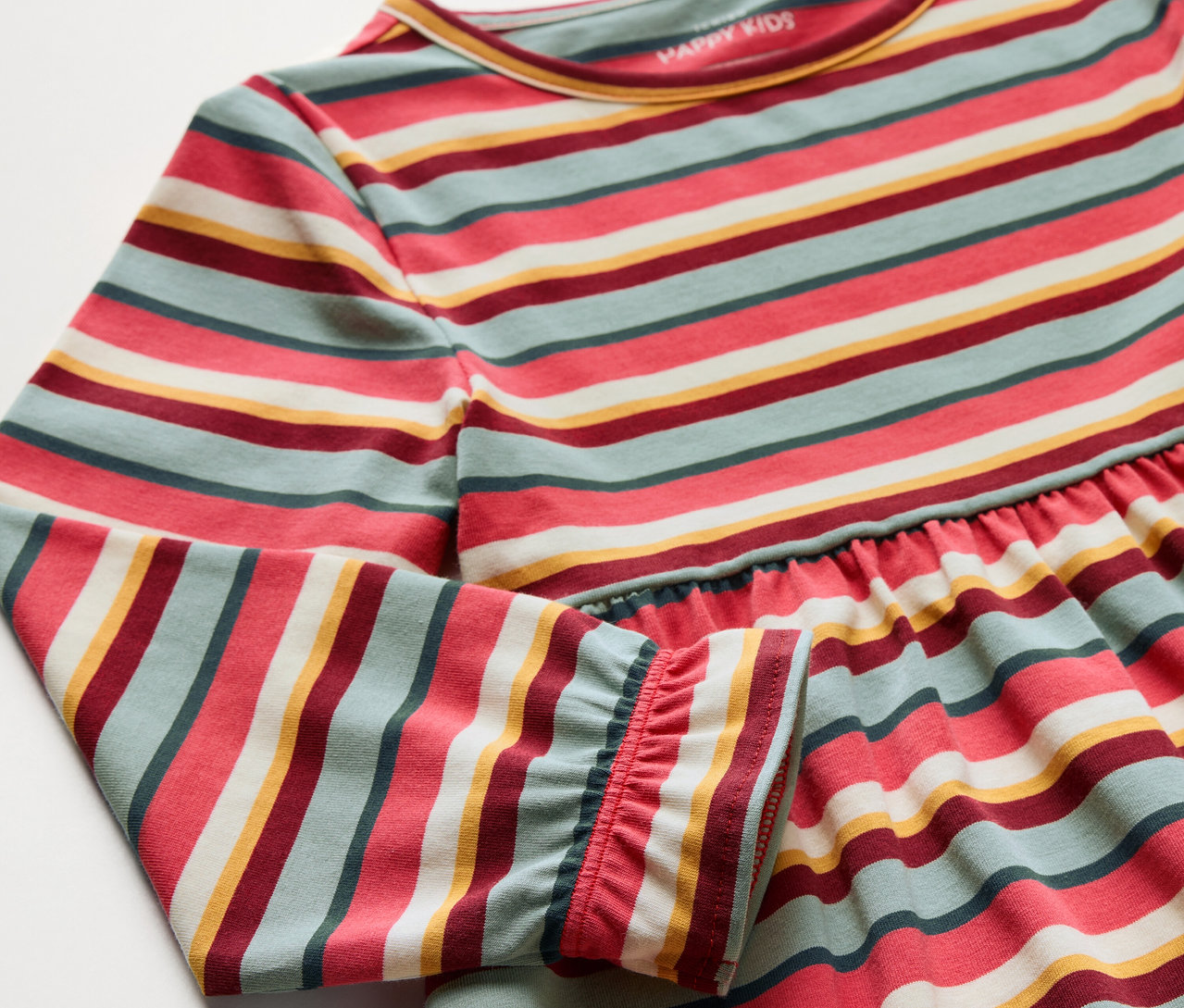 Detailaufnahme eines Kinder-Jerseykleids mit bunten Streifen.