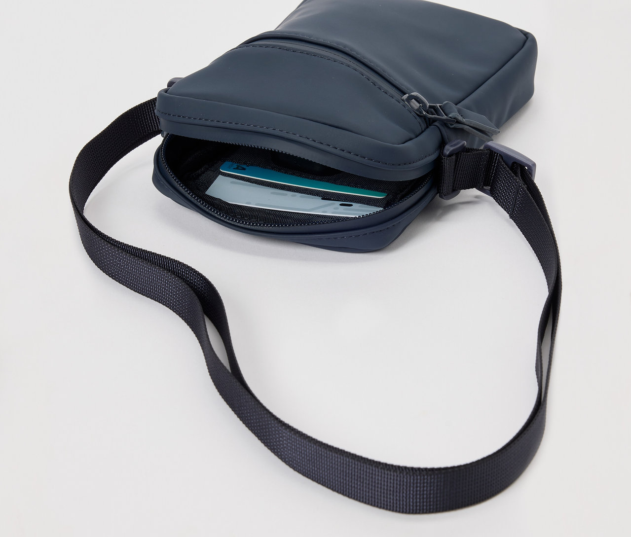Marineblaue Regen-Umhängetasche mit schwarzem Riemen und Karten innen.