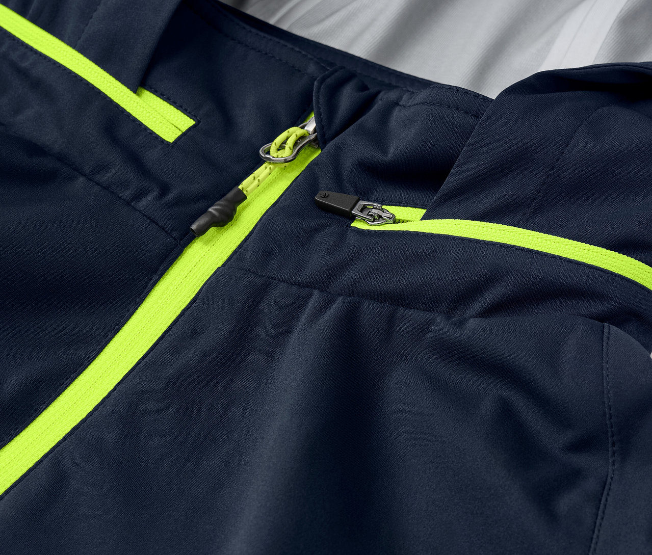 Detailansicht einer Rad-Regenjacke mit neongelben Reißverschlussdetails und Paspeln.