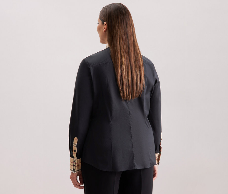 Rückansicht einer Frau mit langen braunen Haaren, die eine schwarze Seidensticker Popeline-Bluse mit Karodetail trägt.