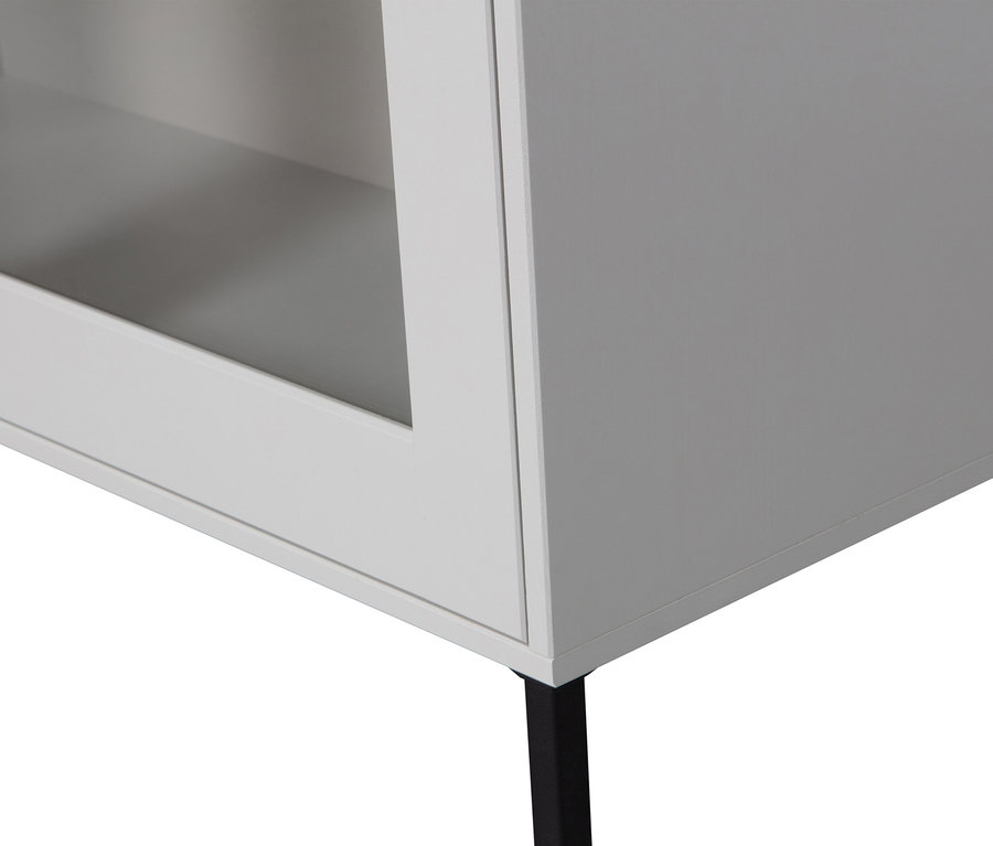 Detailansicht eines weißen Schranks mit einer Glastür und einem schwarzen Bein.