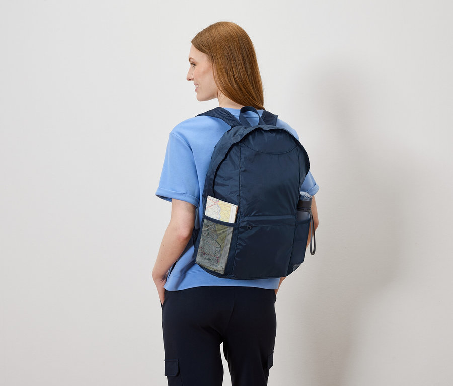 Frau von hinten mit marineblauem Rucksack, in dem sich eine Karte und eine Wasserflasche befinden.
