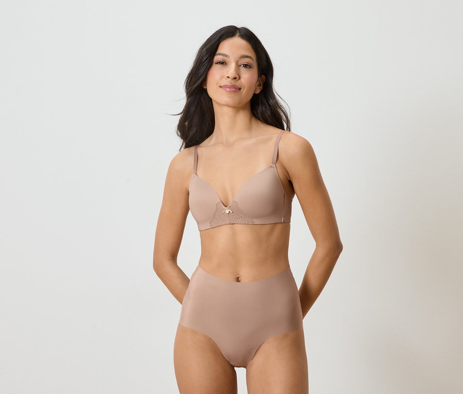 Frau trägt einen hautfarbenen BH und einen Slip, die beide auf einem weißen Hintergrund dargestellt sind.