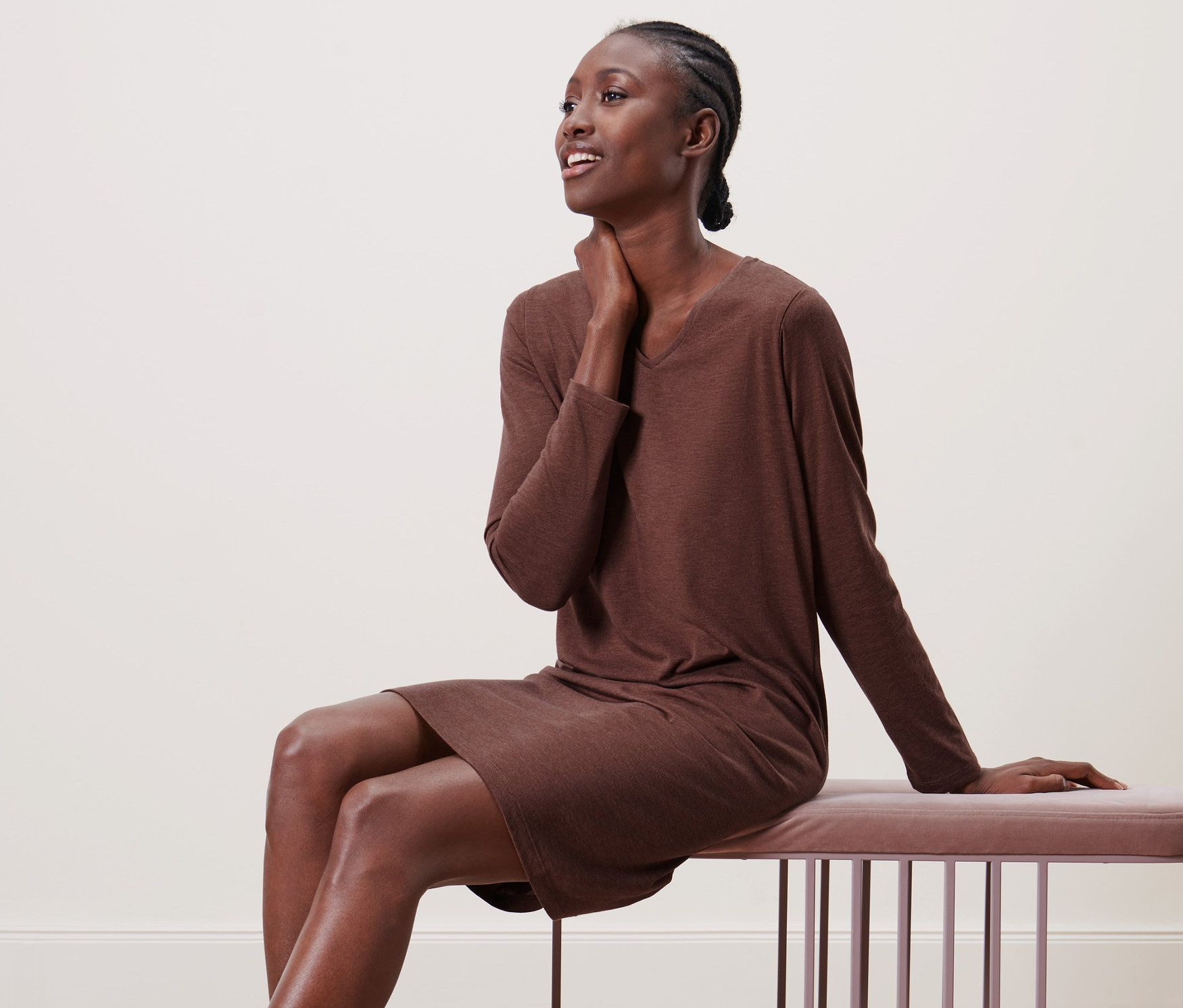 Frau sitzt in einem Nachthemd auf einer Bank.