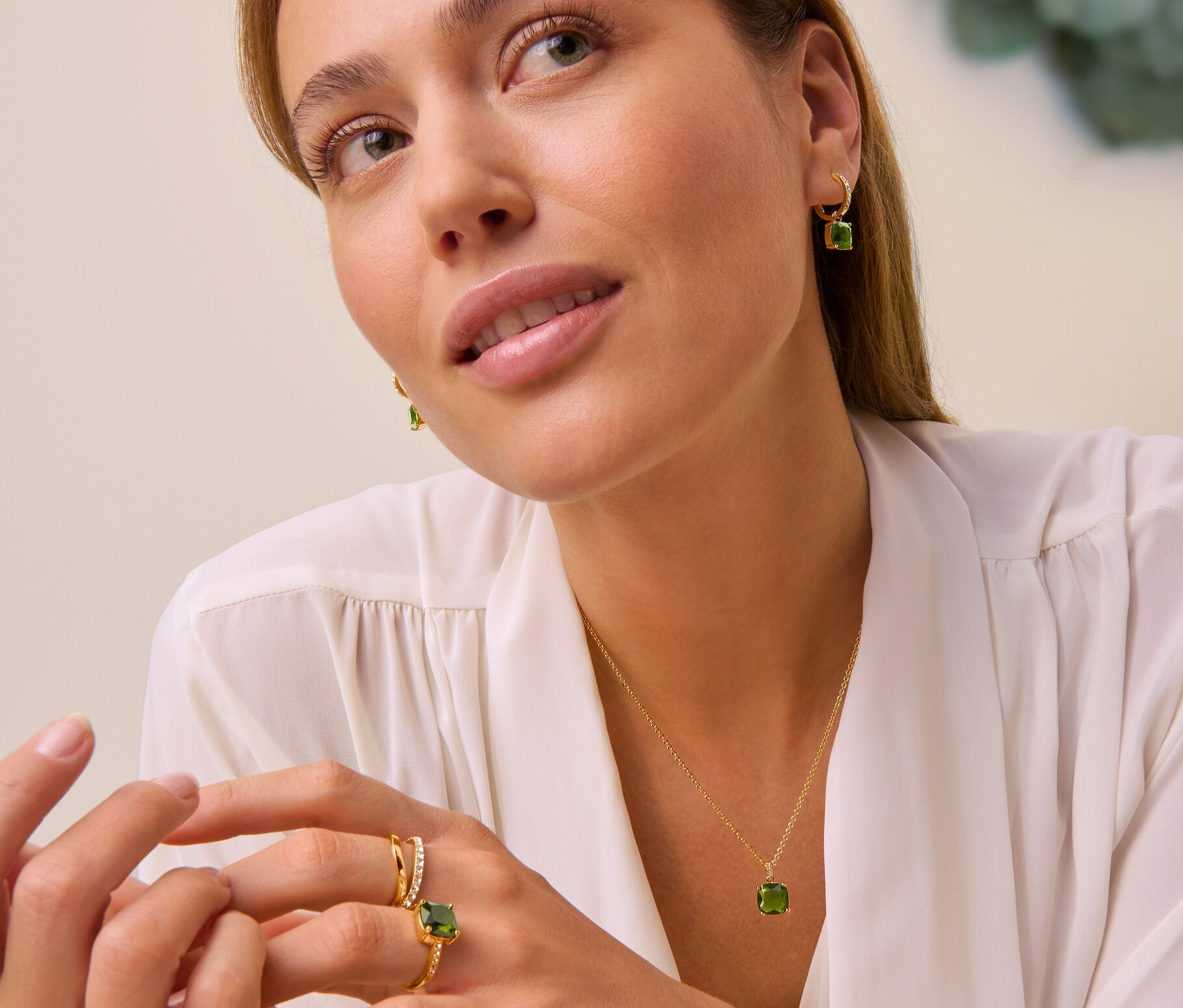 Frau trägt Kette Forest mit grünem Glaskristall, Creolen Forest mit grünem Glaskristall, Ring Forest mit grünem Glaskristall und Ring Doppel-Welle mit Kristallen.