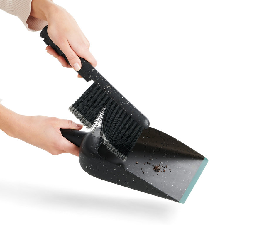 Eine Frau kehrt mit Handkehrer und Schaufel.