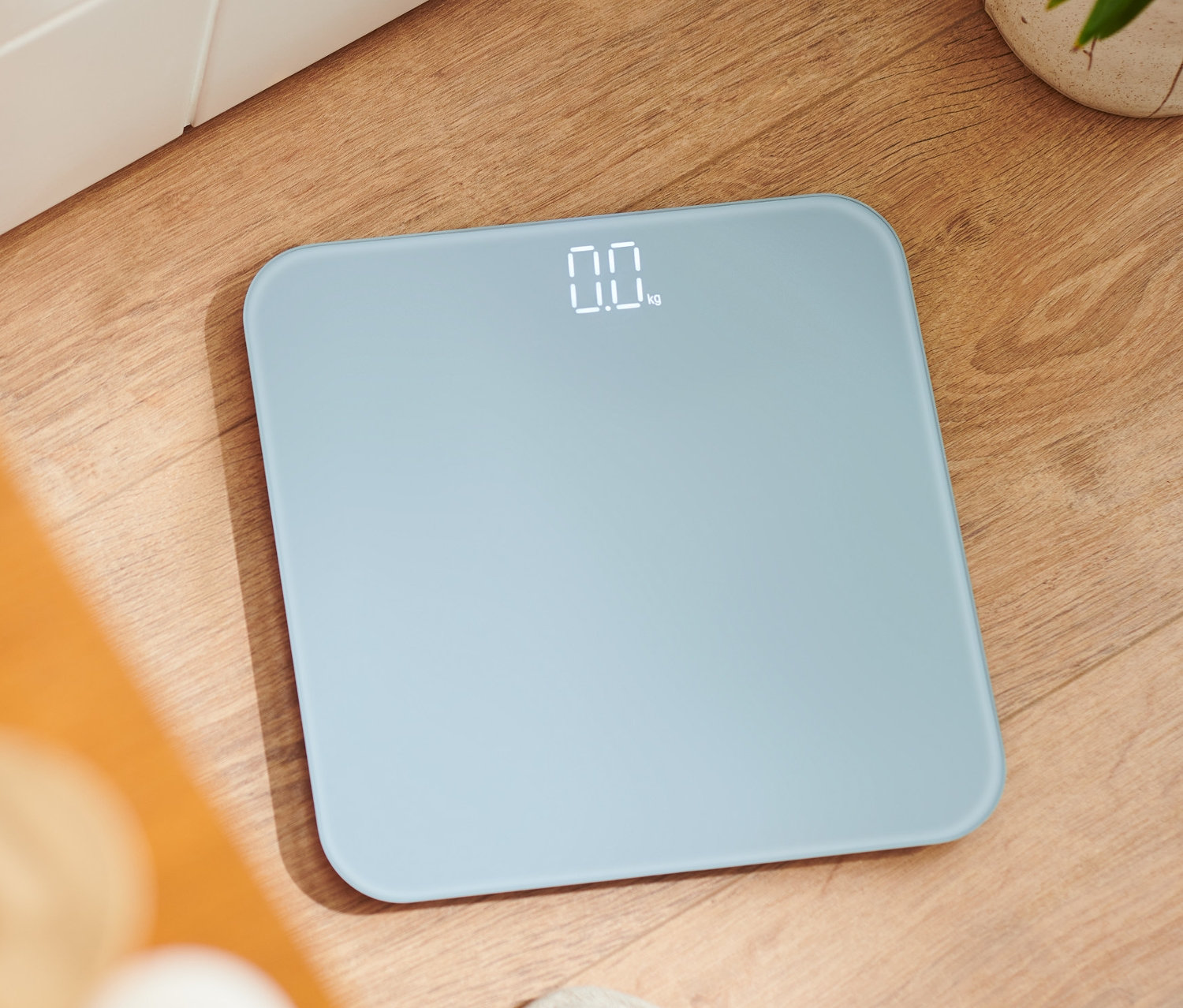 Eine digitale Badwaage steht auf einem Holzboden.