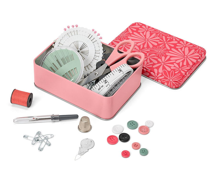 Offene Metallbox mit Näh-Set, daneben eine Spule Faden, ein Fingerhut, Stecknadeln, Knöpfe und ein Nadeleinfädler.