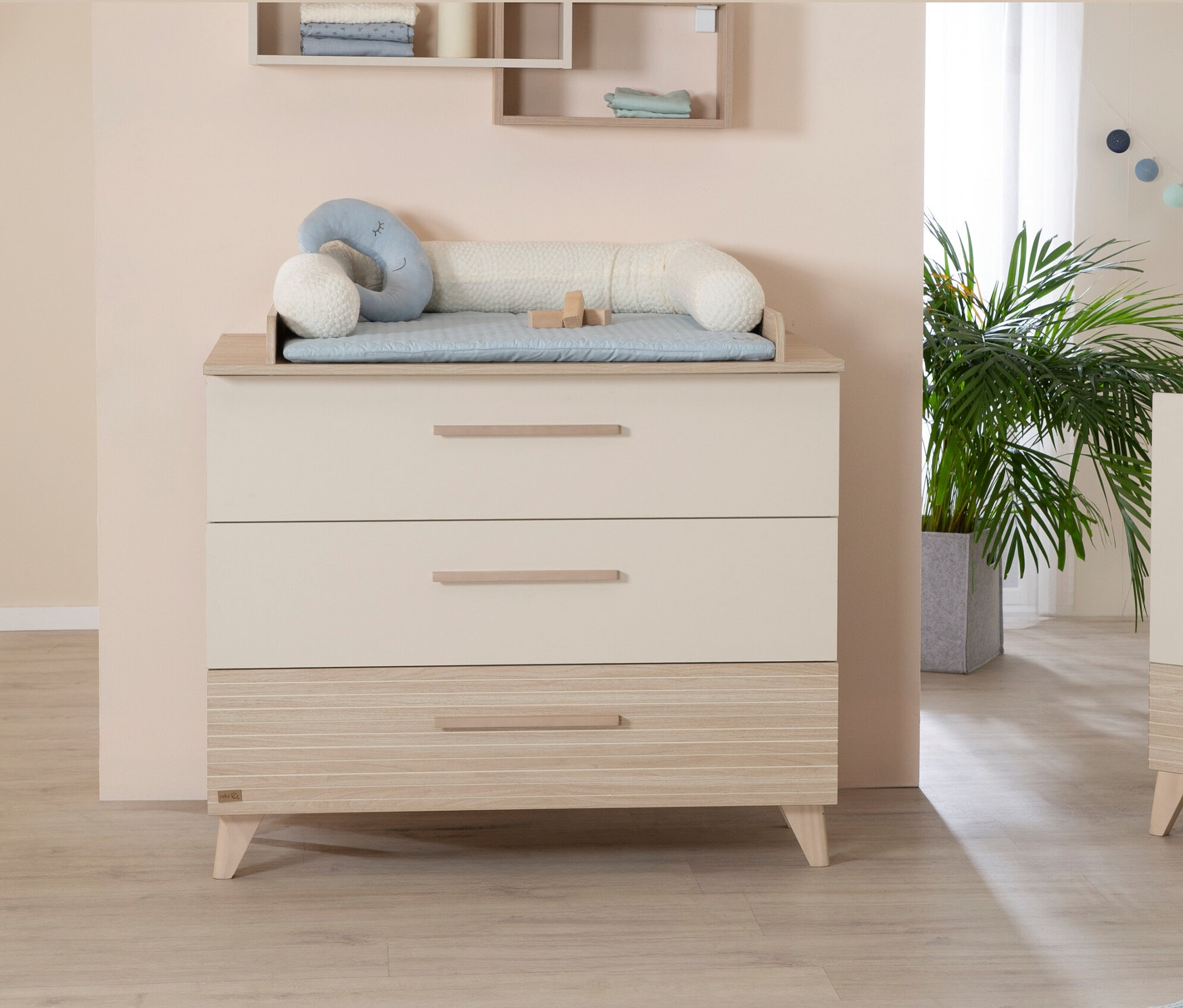 Beige Kommode mit drei Schubladen und einem Wickelaufsatz darauf.