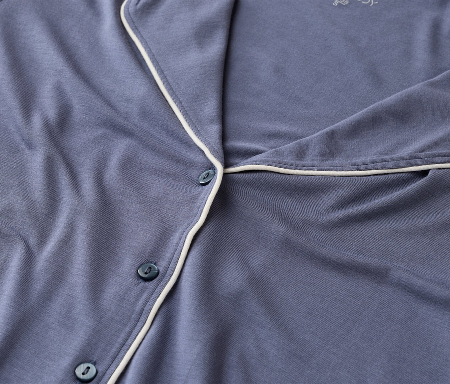 Nahaufnahme eines blauen Pyjamaoberteils mit weißen Paspeln und Knöpfen.