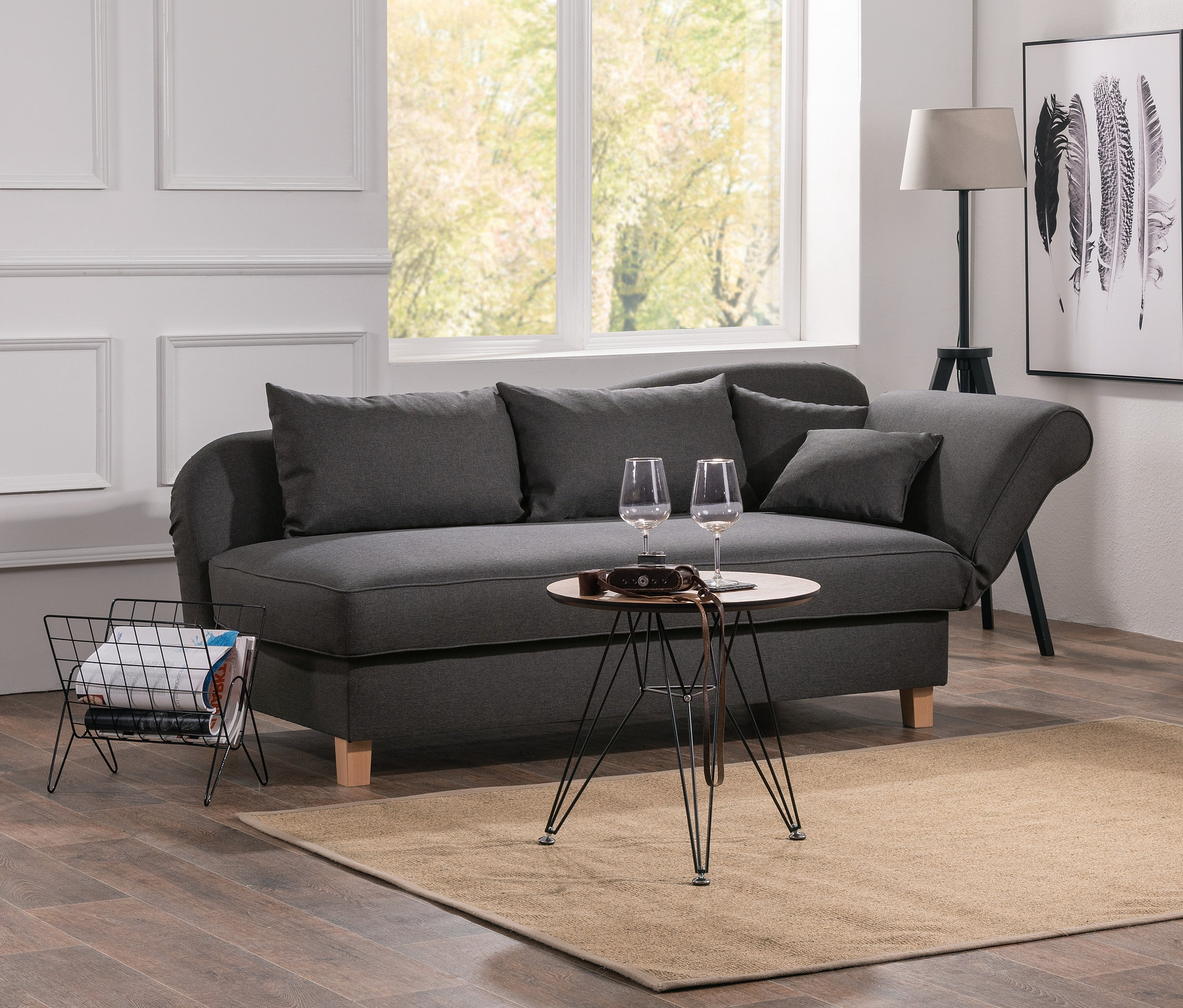 Wohnzimmer mit grauer Recamiere »Saturn« mit Stauraum, Tisch mit Weingläsern und Bücherregal.