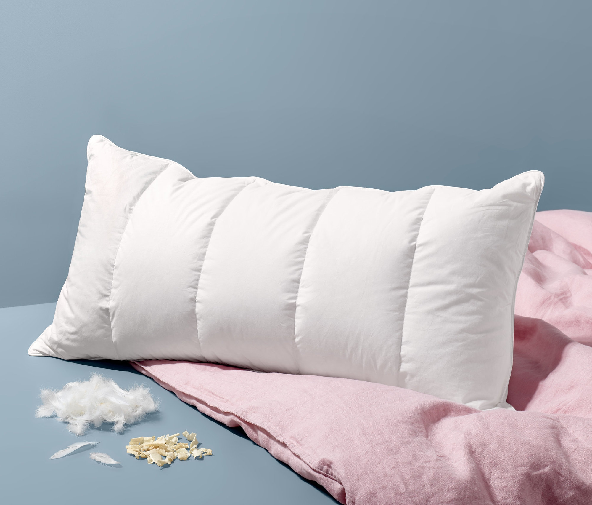 Ein weißes Zirbenkopfkissen, ca. 80 x 40 cm, liegt auf einem rosa Leinenbettlaken.