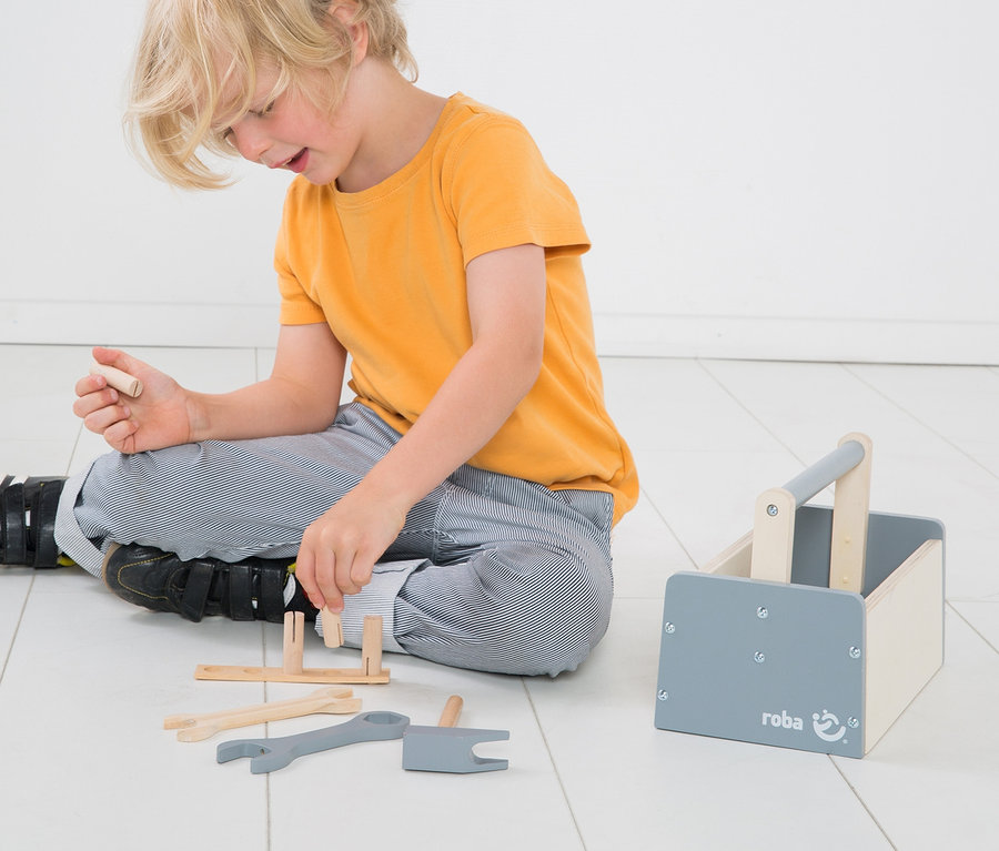 Junge spielt mit roba Werkzeugkiste, 22-teilig, auf dem Boden.