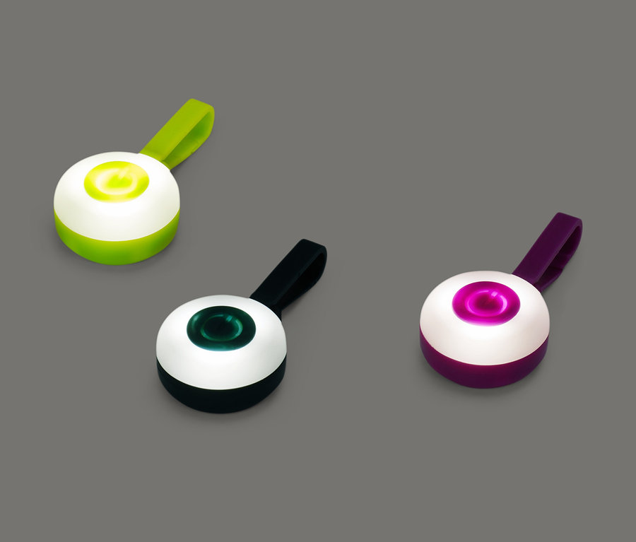 Drei verschiedenfarbige LED-Anhänger liegen auf einem grauen Hintergrund.