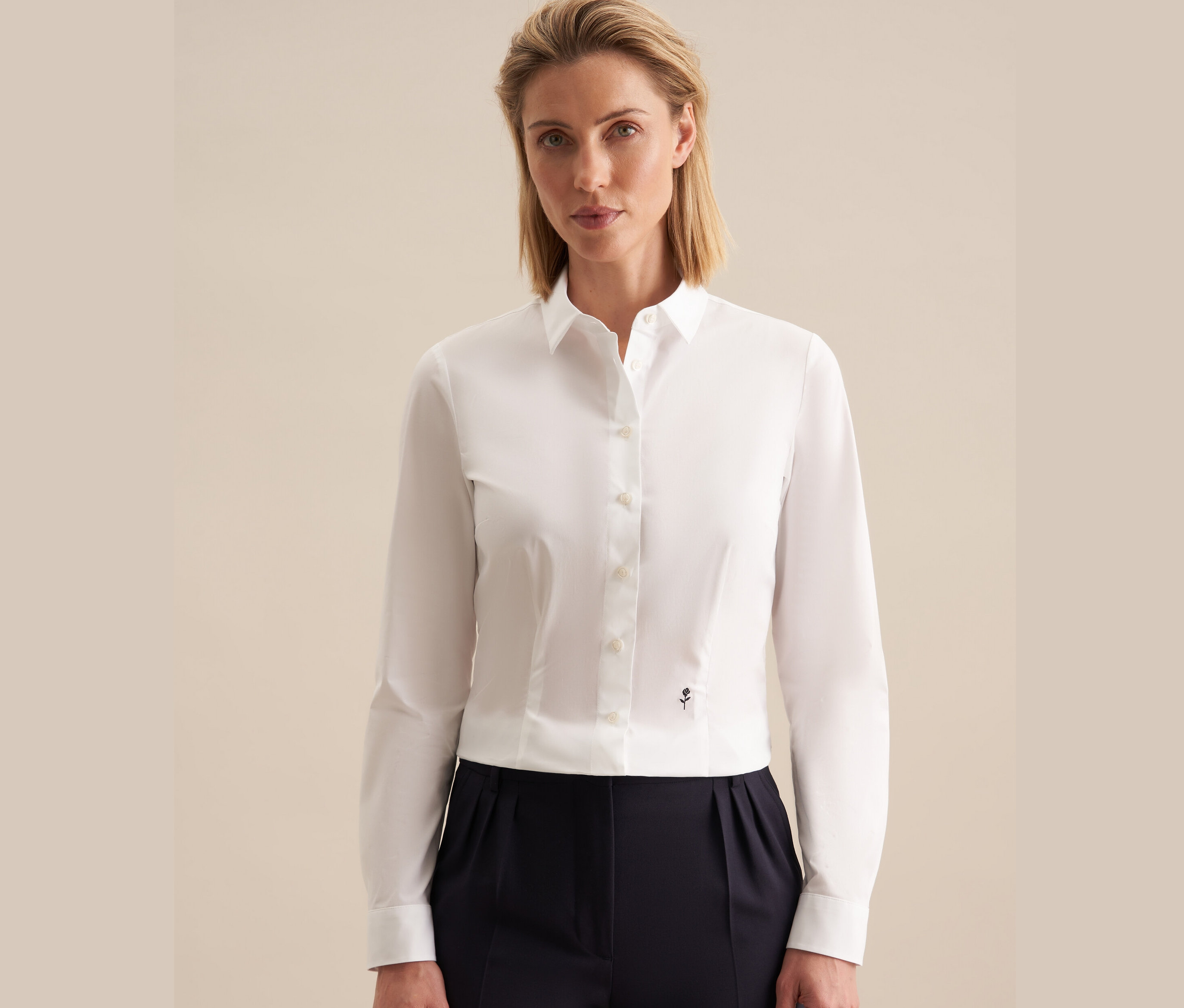 Frau trägt eine weiße Seidensticker Slimfit Bluse und eine dunkelblaue Hose.