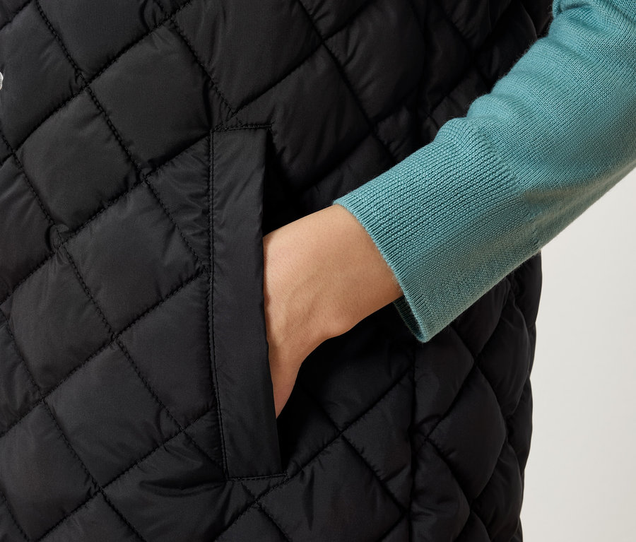 Detailaufnahme einer gesteppten Damenweste mit Hand in der Tasche.