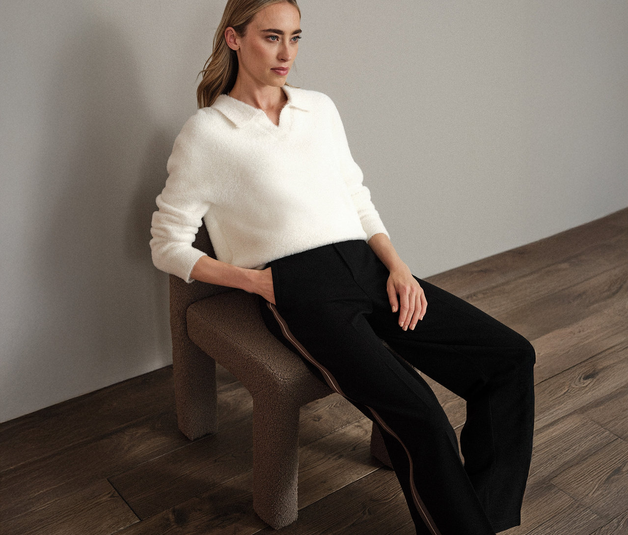 Frau sitzt auf einem Stuhl und trägt einen weißen Street One Strickpullover mit Polokragen.