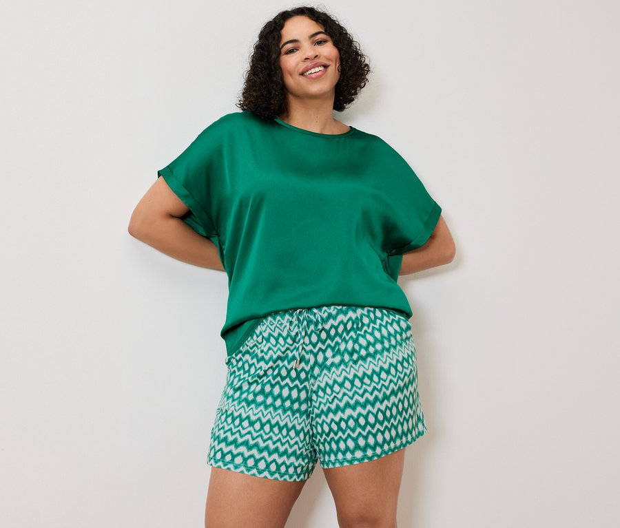 Frau posiert in einem Blusenshirt im Materialmix, aqua, und 2 Jerseyshorts.