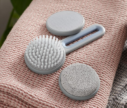 Ein Fußpflege-Set liegt auf einem rosa Handtuch, neben einer braunen Flasche mit Spender.