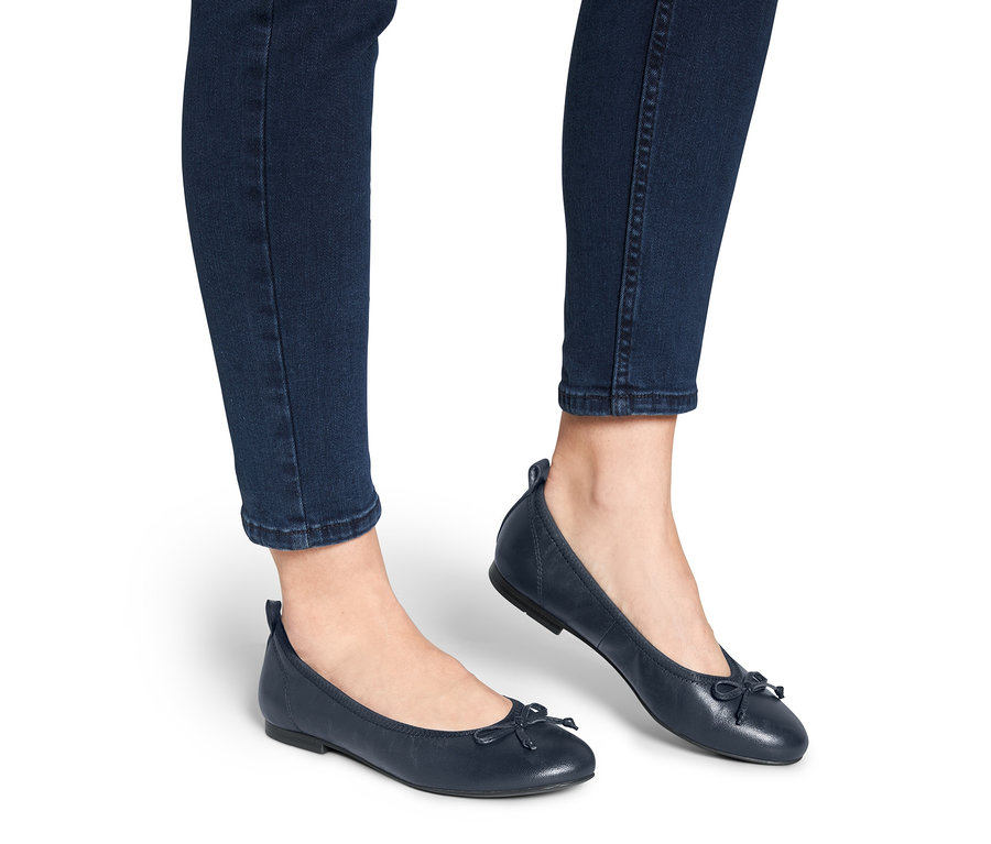 Beine in Jeans tragen blaue Leder-Ballerinas.