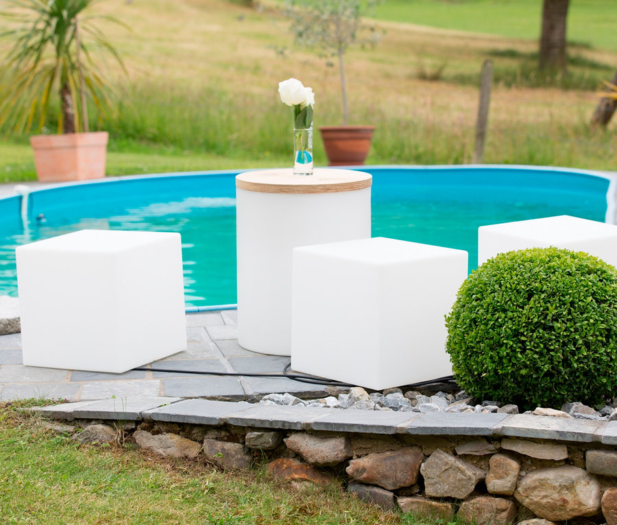 Am Pool stehen vier 8 seasons design LED-Leuchtwürfel, 43 cm und ein weißer Tisch.