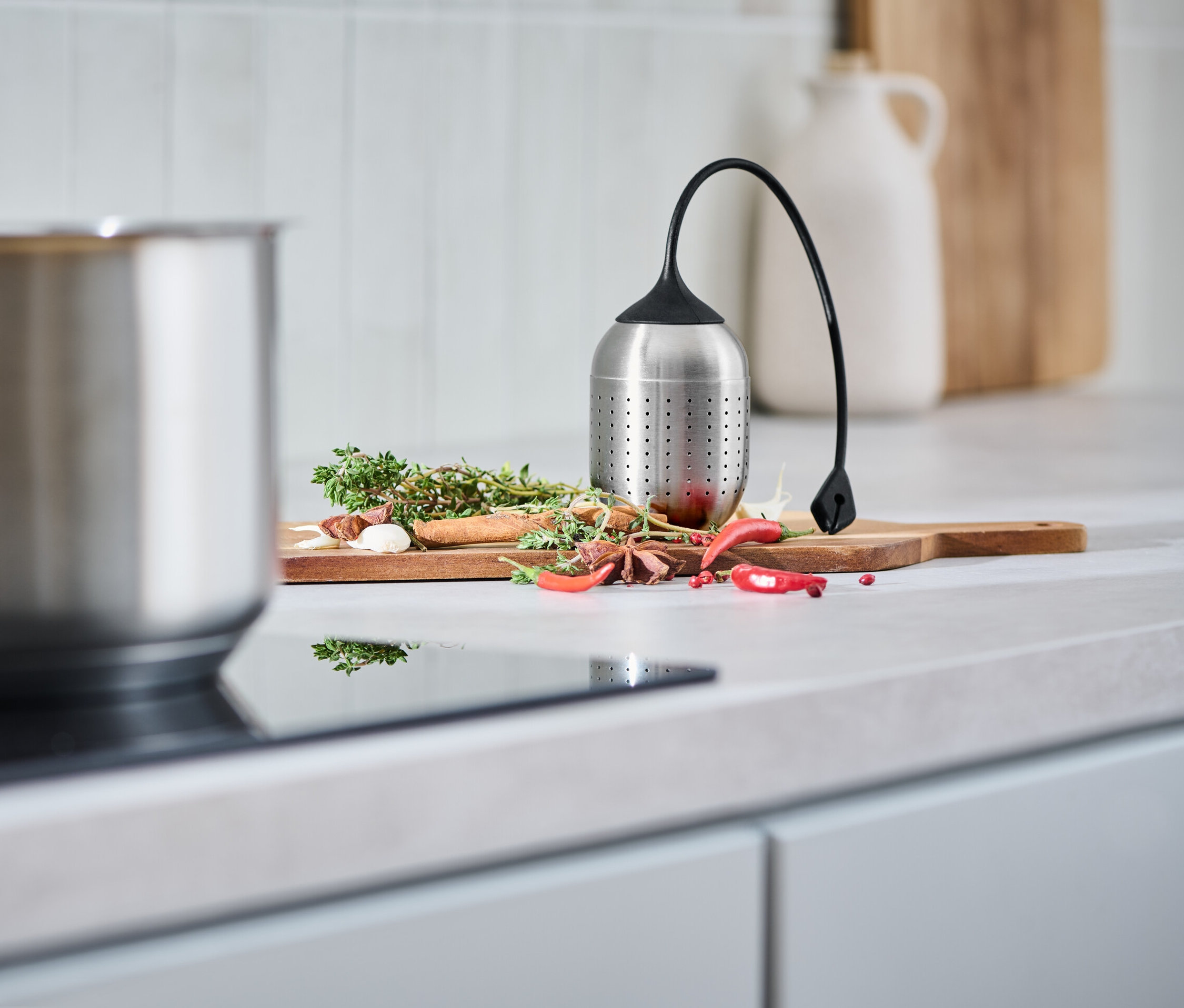 Gewürze und eine Gewürzkugel liegen auf einem Schneidebrett.