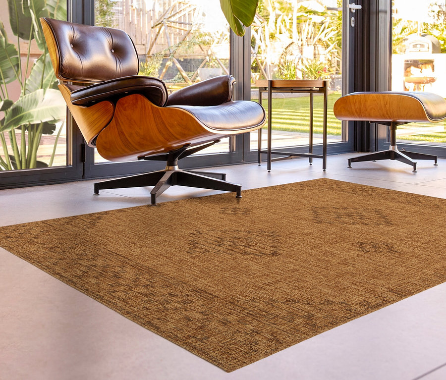 Ein brauner Teppich »Roy« liegt in einem Wohnzimmer mit einem braunen Ledersessel.